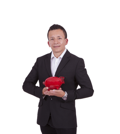 Image of a smiling young businessman posing with a piggy bank while standing against whiteの写真素材