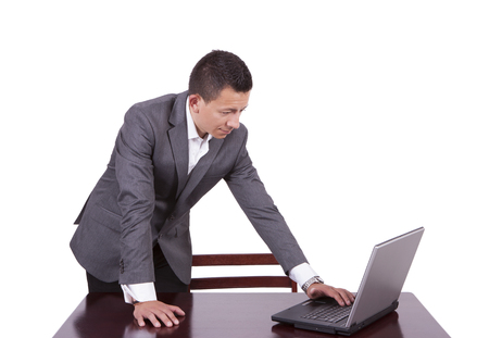 Young businessman standing and using laptop at workの写真素材