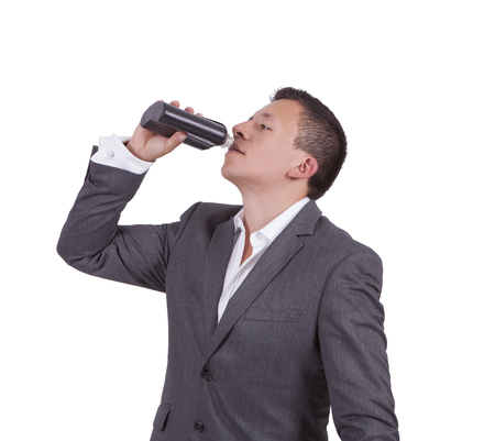 Image of a handsome young businessman drinking water while standing against whiteの写真素材