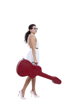 Side view of an attractive young female posing with guitar caseの写真素材