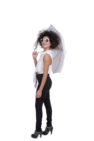 Side view of an attractive young woman posing with sunglasses and umbrella against white backgroundの写真素材