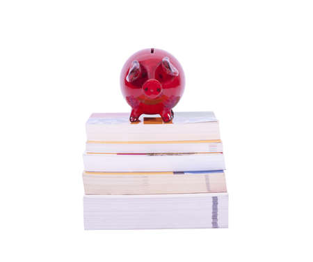 Red piggy bank on stack of books isolated on white backgroundの写真素材