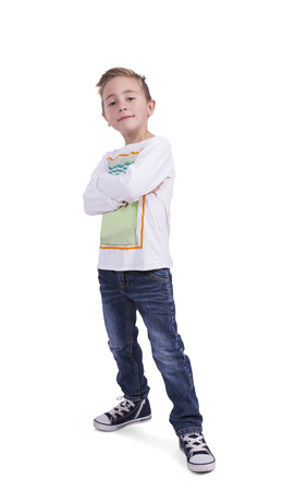 Cute elementary boy with arms crossed posing against white の写真素材