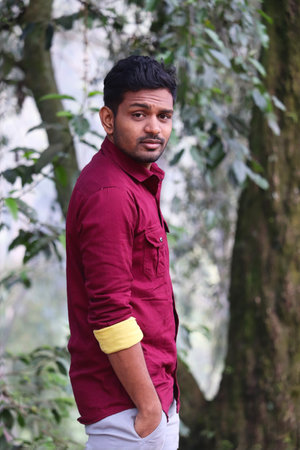 indian man in red shirt and white pants standing in the forestの写真素材