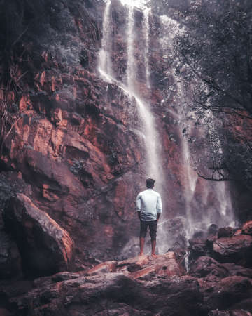 Man standing in front of a waterfall in the forest. Travel and adventure concept.の写真素材