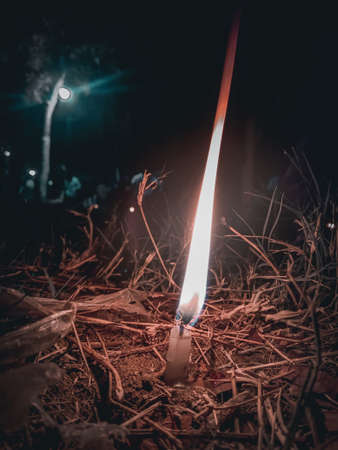 Burning candle on the ground in the forest at night. Selective focus.の写真素材