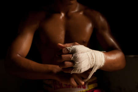 The muscular fighter tying tape around his hand preparing to boxの写真素材