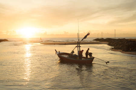 fisherman on boat in the sunrise, Thailandの写真素材
