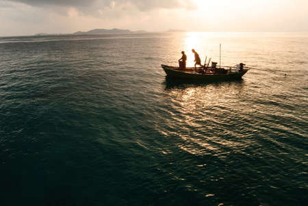 Fisherman on boat in morningの写真素材