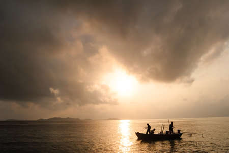 silhouette of fishermen with they boatの写真素材