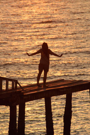 Man with his hands up watching the sun setの写真素材