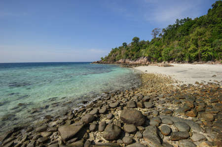 A rocky sand beach and beautiful coral is seen through the crystal clear water of island paradise, Koh Lipe in Thailand.の写真素材