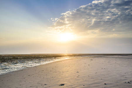 Beautiful low point of view along beach at low tide out to sea with vibrant sunrise skyの写真素材