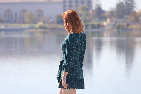 Photo of a Beautiful white girl in a beautiful dress standing in front of a lakeの写真素材