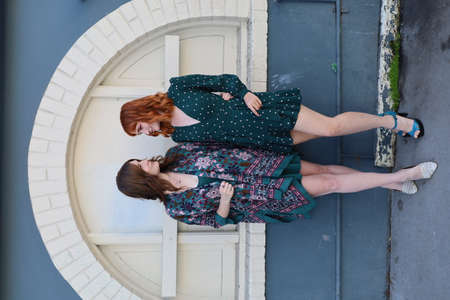 Photo of two white girls in beautiful dresses near a buildingの写真素材