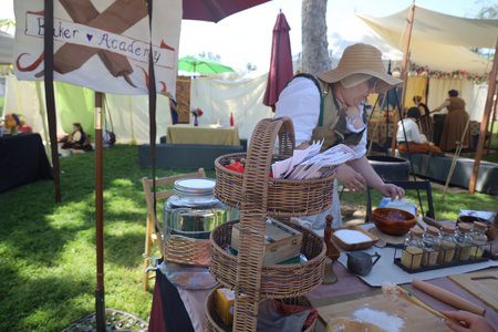 4-15-2023: Visalia, California: Woman in period costumes at a Renaissance Faire, baking breadのeditorial素材
