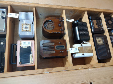 A collection of vintage radio sets in a wooden shelf in a store