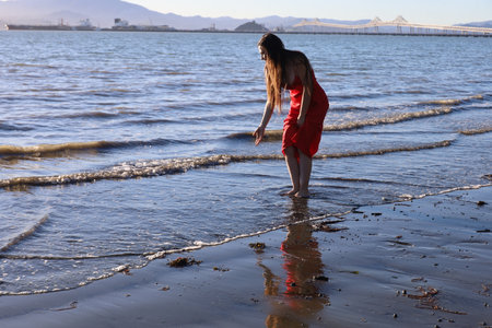 Photo of a beautiful white lady standing on a beach near the water