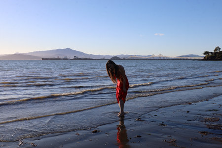 Photo of a beautiful white lady standing on a beach near the water