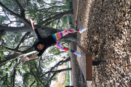 Photo of a mature woman jumping off a bench in a park