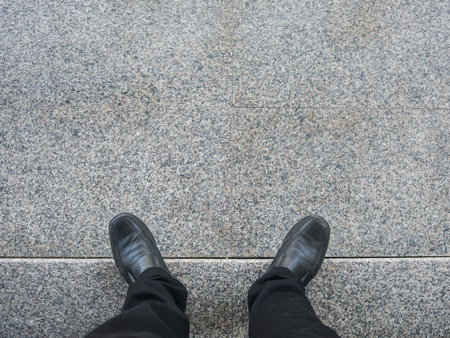 Business man looking down to his feet while standing on stair.の写真素材
