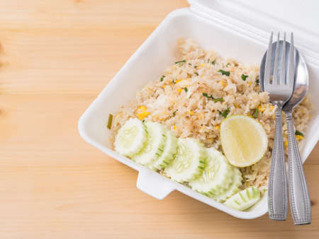Fired rice with sliced cucumber and lemon, Thai style food in foam package.
