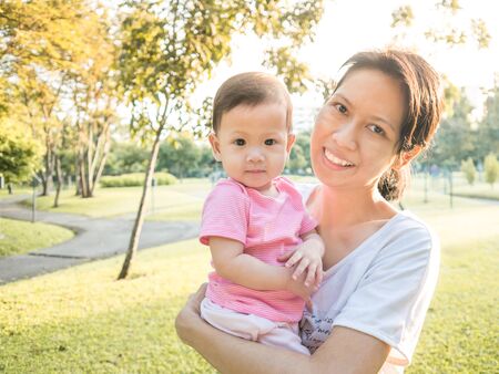 Asian mother carrying her baby in garden in morning.の写真素材