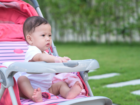 Asian baby girl look joyful sitting in stroller.の写真素材
