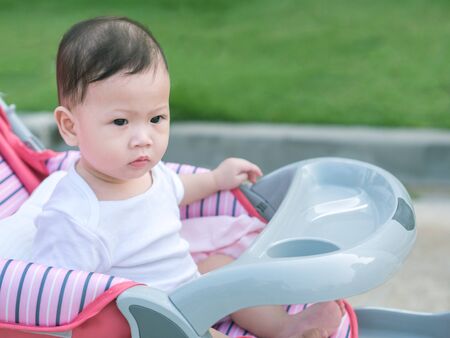 Asian toddler sit in stroller outdoor morning.の写真素材