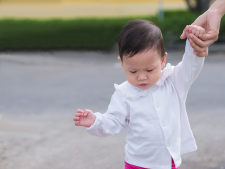 Asian toddler is learning walking step by step outdoor.