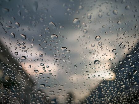 Raindrops on car glass and blurry village.