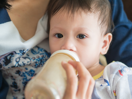 Asian mother feed milk her baby by bottle. Asian family parenting.の写真素材
