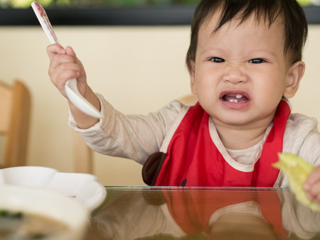 Asian toddler learn to eat meal herself.の写真素材