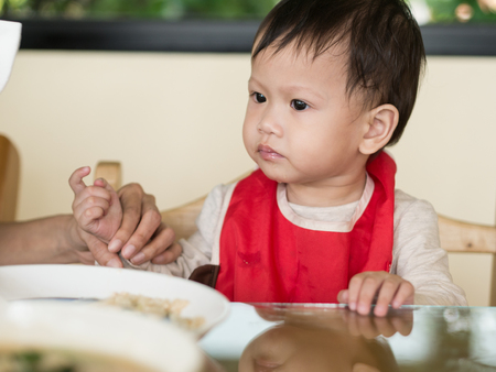 Asian toddler learn to eat meal herself.の写真素材