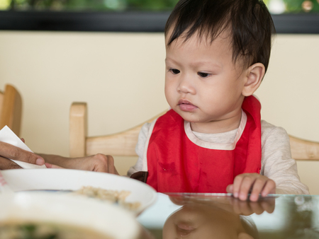 Asian toddler learn to eat meal herself.の写真素材