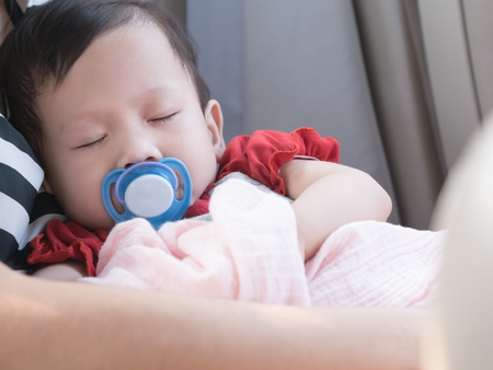 Baby sleep in car with pacifier in mouth. Asian toddler sleep in mom hand.の写真素材