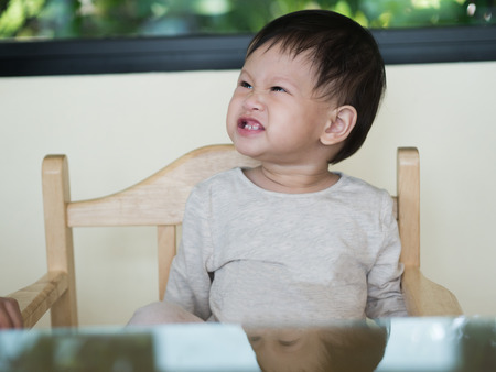 Toddler titter while sitting on table. Looks happy.の写真素材