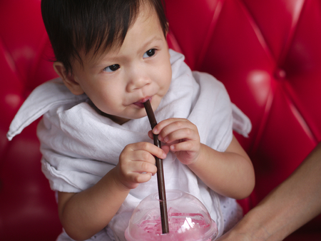Asian baby drinking iced sweet pink beverage.の写真素材