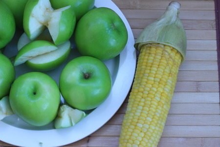 Green apple that was placed near sliced boiled cornの写真素材