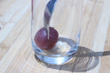 Grapes in a glass with a fork inserted on a brown backgroundの写真素材
