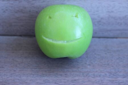Apple carved with a knife, a beautiful smile on a gray backgroundの写真素材