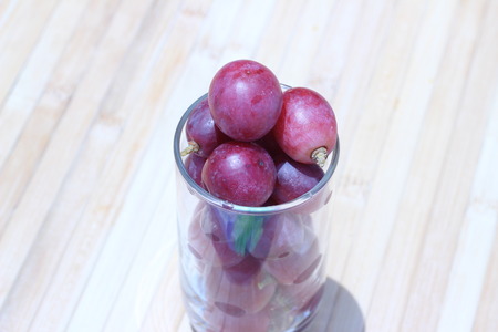 Grapes in a glass placed on a brown backgroundの写真素材