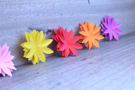 Many colorful paper flowers on a background with a smooth surfaceの写真素材