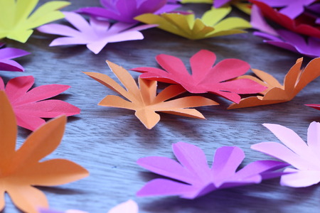 Many colorful paper flowers on a background with a smooth surfaceの写真素材