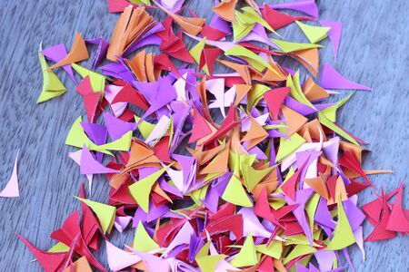Beautiful colored paper cut into small pieces and piled on the old wooden gray backgroundの写真素材