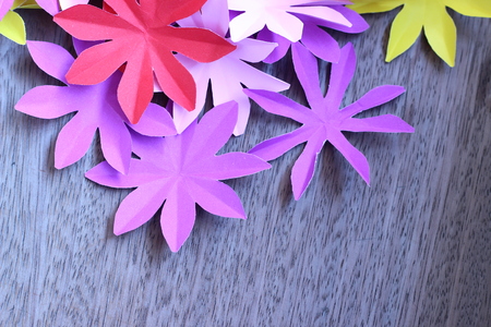 Many colorful paper flowers on a background with a smooth surfaceの写真素材