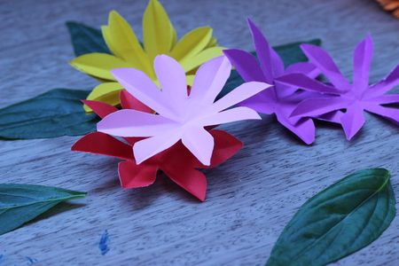 Many colorful paper flowers on a background with a smooth surfaceの写真素材