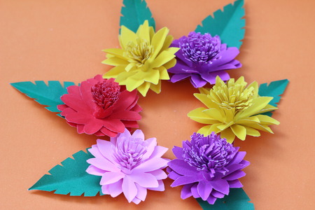 Many colorful paper flowers on a background with a smooth surfaceの写真素材