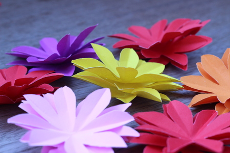 Many colorful paper flowers on a background with a smooth surfaceの写真素材