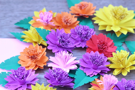Many colorful paper flowers on a background with a smooth surfaceの写真素材